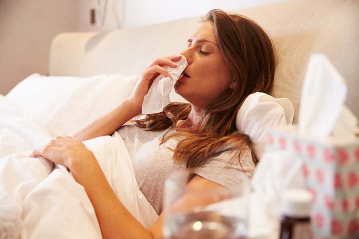 woman in bed blowing nose